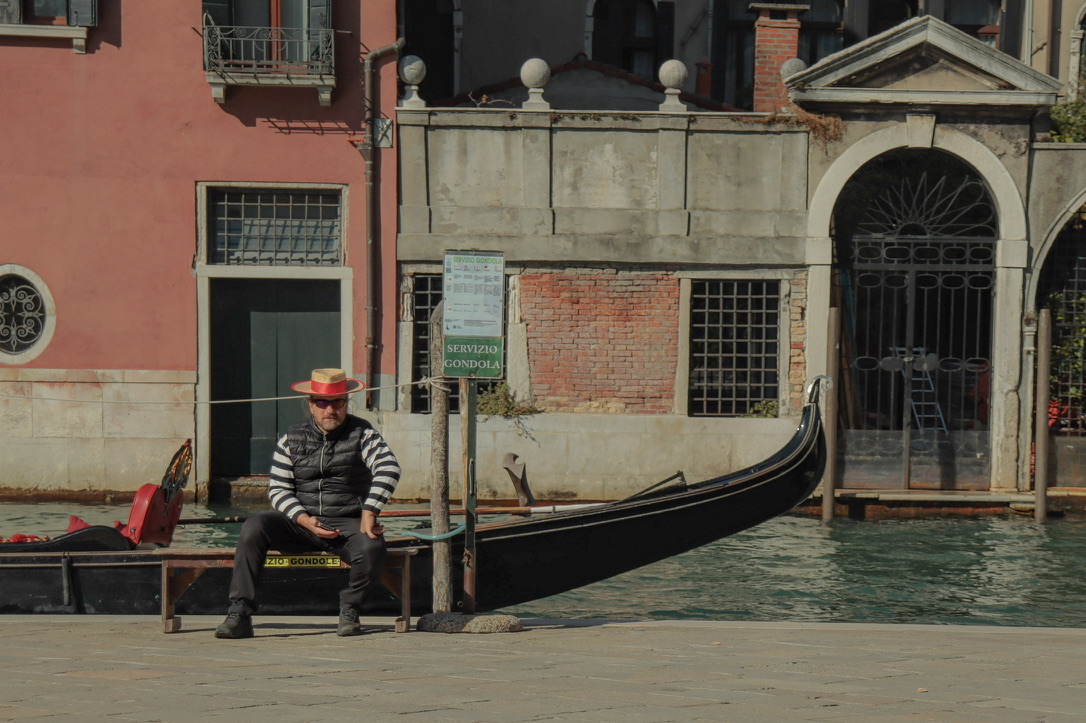 A solitary human anchor framed beside ancient canal facades.